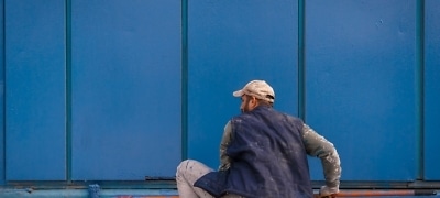 Schilder verft een blauwe buitenmuur met een verfroller